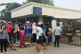 People stand outside Ateneo de Zamboanga University after a shooting that killed two people on Aug. 18.